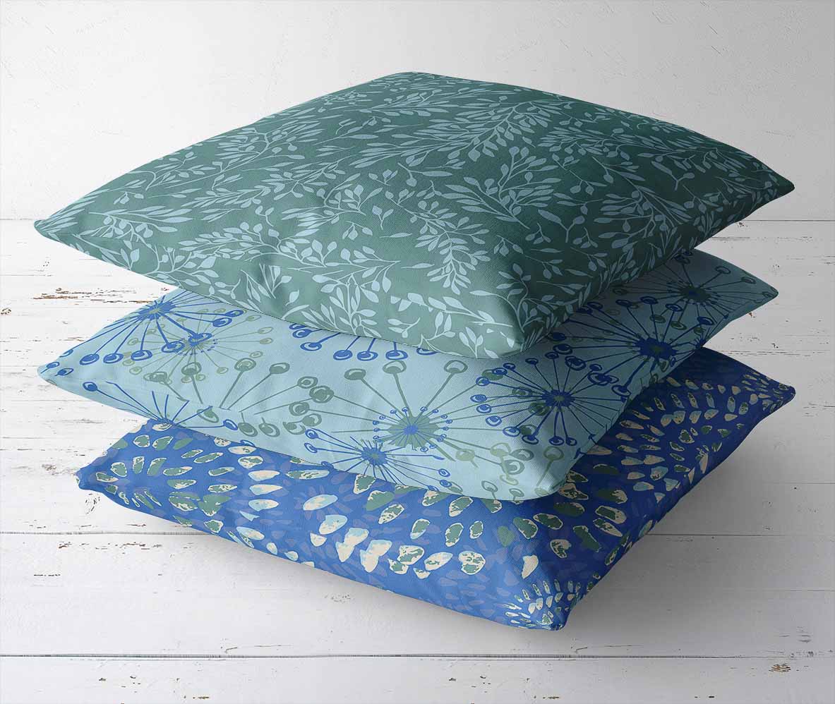 throw pillows with the patterns Raindrops, Swirling, and Lovely Laurels in blue and teal. Lakeside Connections Collection